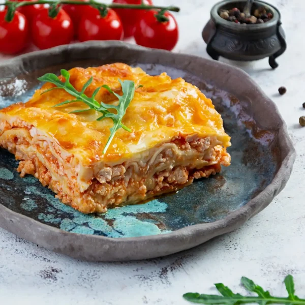 Rakott étel tányéron, rukkolával, paradicsommal tálalva