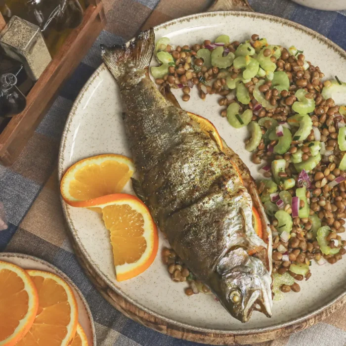 Sült egész pisztráng zelleres lencsesalátával, narancskarikával tálalva tányéron
