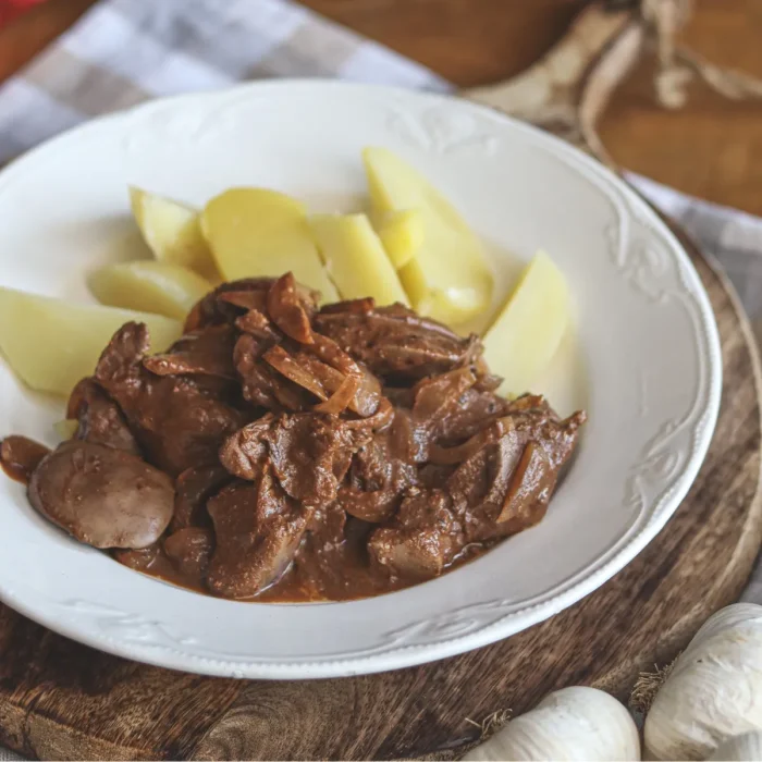 Resztelt máj fehér tányérban, főtt krumplivl tálalva