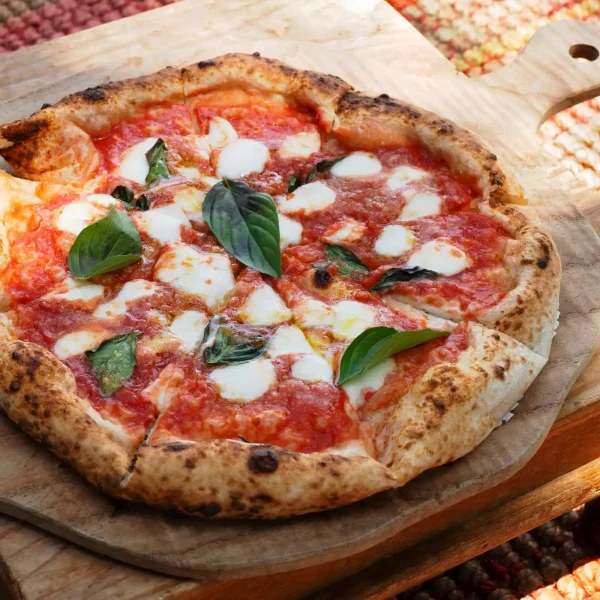 Paradicsomszószos pizza bazsalikomlevéllel, mozzarella sajttal fa deszkán tálalva