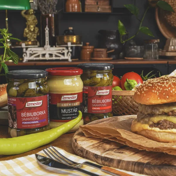 Sajtburger húspogácsával fa deszkán, mellette bébiuborka savanyúság, mustár