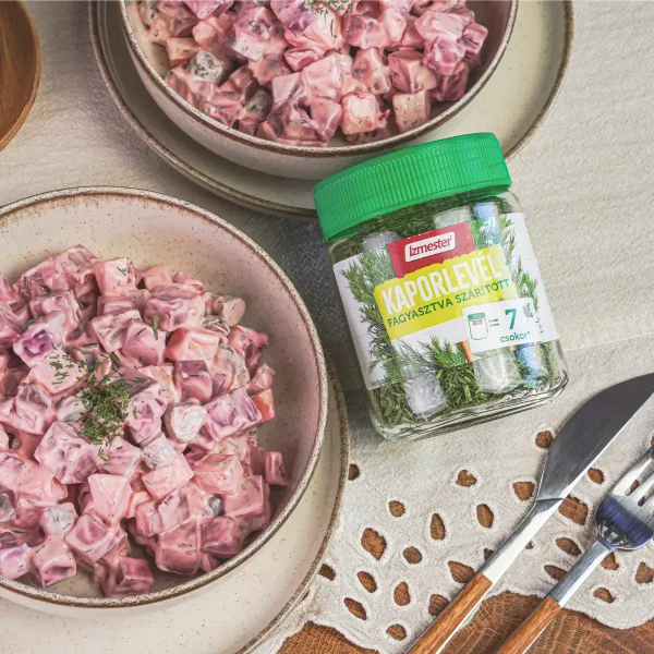 Majonézes céklasaláta kaporlevéllel megszórva egy salátás tálban, fa asztalon, fagyasztva szárított üveges kaporlevéllel tálalva