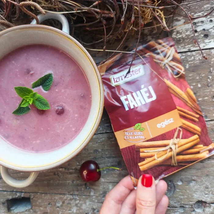 Meggyleves fehér tálban, mellette egy 1 tasak egész fahéj