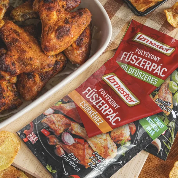 Grillezett csirkeszárny fehér tálban mellette egy tasak Ízmester folyékony fűszerpác csirkéhez