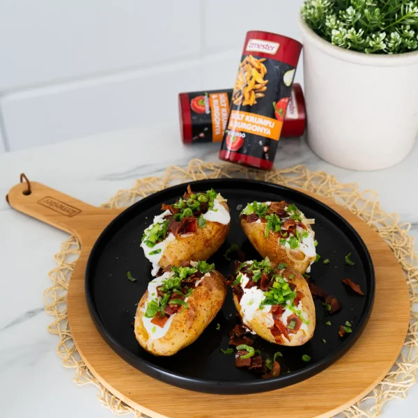 Egy fekete tányéron asztalra helyezve jacket potato töltött burgonya baconnel, tejföllel, metélőhagymával megszórva, mellette szórófejes sült krumpli fűszerkeverék termék