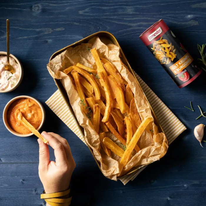 Sütőben sült hasábburgonya tepsiben felülnézetből szósszal és fűszerrel