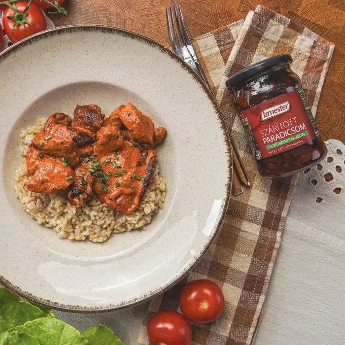 paprikás-tejszínes szósszal készült sült hús rizzsel tálalva tányéron, mellette Ízmester szárított paradicsom üvegben