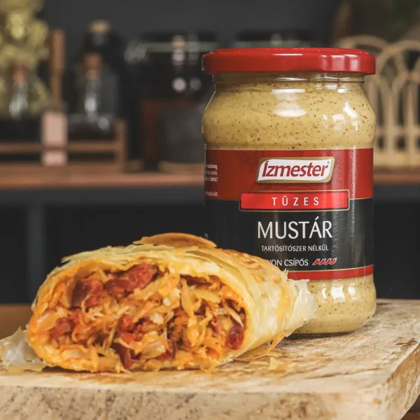 Káposztás, kolbászos házi rétes fa deszkán félbevágva, mellette üveges csípős mustár