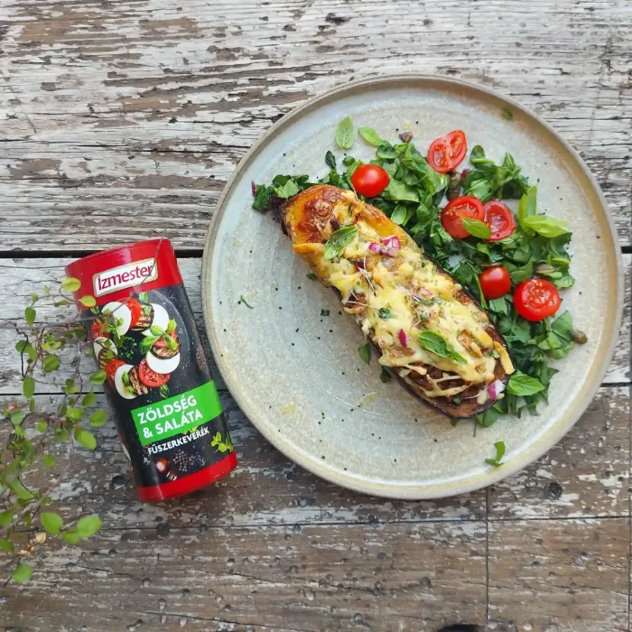 Töltött padlizsán zöldsalátával fehér tányéron felülnézetből, mellette egy doboz zöldség és saláta fűszerkeverék