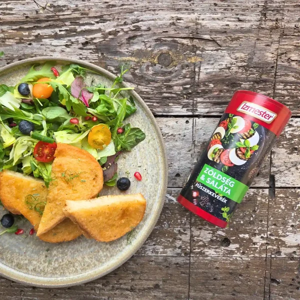 Vegyes saláta pirítóssal világos tányéron felülnézetből, mellette egy doboz zöldség és saláta fűszerkeverék