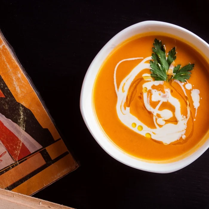 Paradicsomkrémleves felülről fotózva egy fehér tálban, tejszínnel és friss petrezselyemmel díszítve