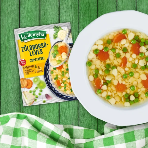 Zöldborsóleves csipetkével házias stílusú levespor tasak faerezetes asztalon, mellette fehér tányérban zöldborsóleves csipetkével és zöld-fehér kockás terítővel