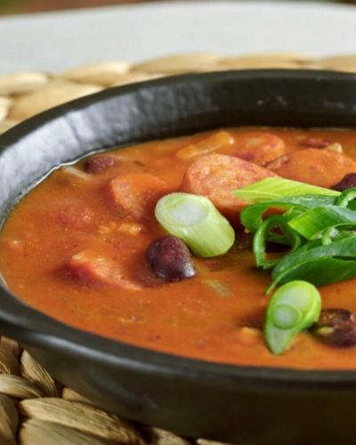 babgulyás tartalmas leves fekete tálban, hagymával tálalva