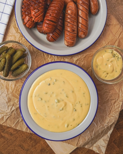 Házi cheddar szósz sült kolbásszal, uborka savanyúsággal tálalva