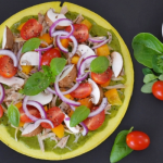 Csirkés gombás spenótos saláta egy tálban, lilahagymával, paradicsommal