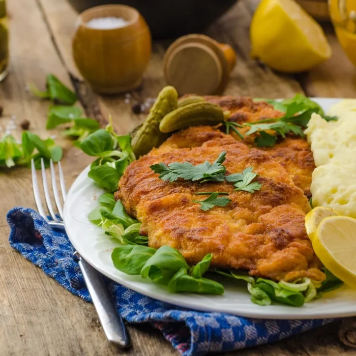 Rántott hús aranybarna bundában tányéron, salátaágyon, bébiuborkával tálalva