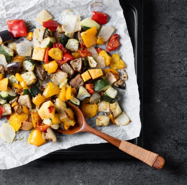 Sült zöldségek tepsiben szétterítve, sült paprika, cukkini, padlizsán, hagyma.
