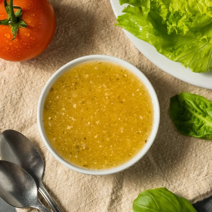 Mustáros vinaigrette szósz felülnézetből egy asztalon, mellette saláta, paradicsom dekoráció