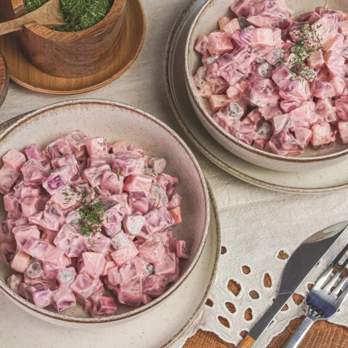 Majonézes céklasaláta kaporlevéllel megszórva egy salátás tálban, fa asztalon, kaporral tálalva