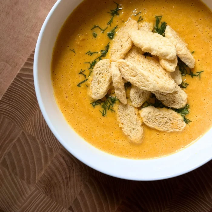 Sütőtök főzelék leves fehér tányérban, pirított kenyérdarabkákkal és kaporlevéllel tálalva