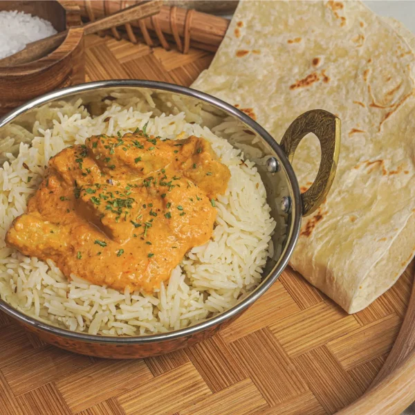 Indiai vajas csirke pitával és rizzsel tálalva asztalon, mellette keleti csirke tasakos fűszerkeverék és só bambusz tálban