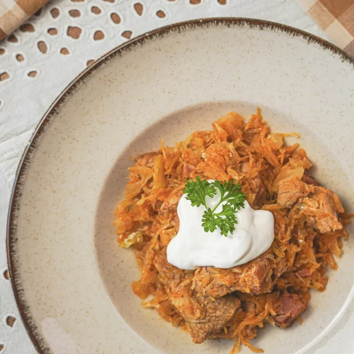 Székelykáposzta hússal, tejföllel felülről fotózva tányéron, petrezselyemlevéllel tálalva