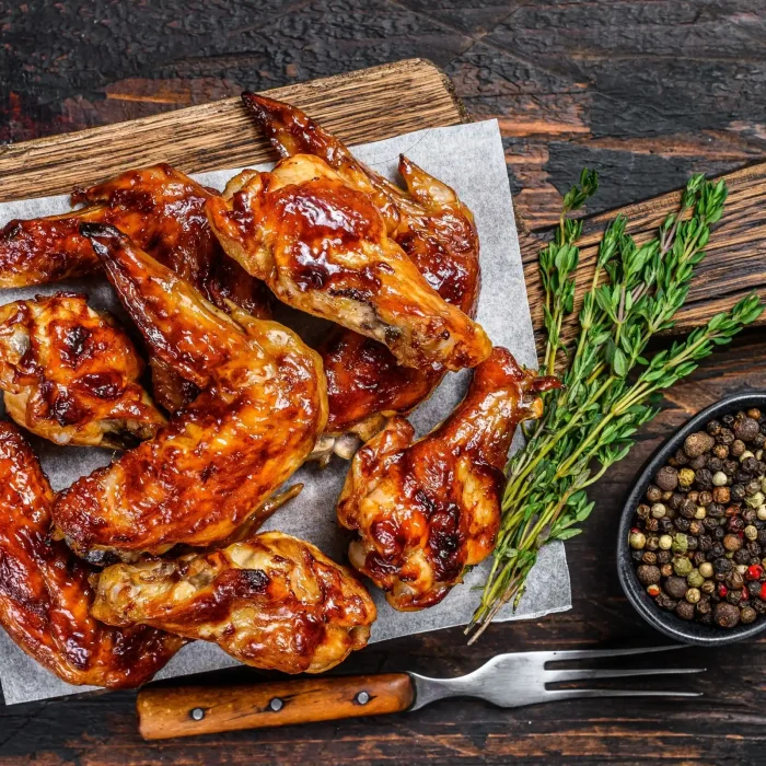 Sült csirkeszárnyak fehér papíron, fadeszkán felülnézetből