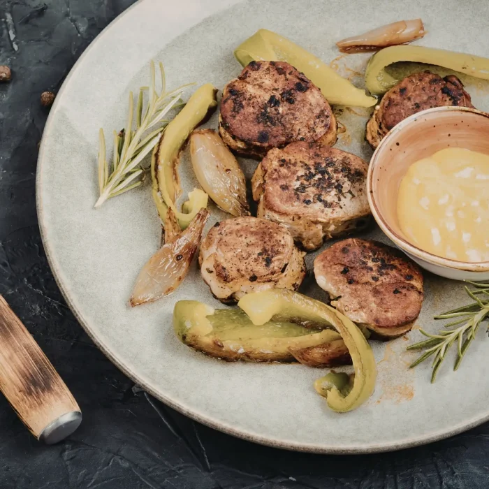 Sült sertéshús tormakrémes mártással tálalva fehér tányéron rozmaringgal