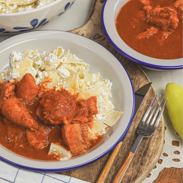 harcsapaprikás túrós csuszával fehér tányérban mellette evőeszközök