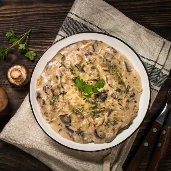 Sűrű tejszínes gombás krém fehér tányérban asztalon