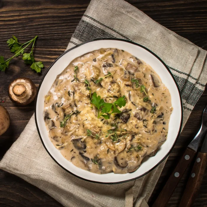 Sűrű tejszínes gombás krém fehér tányérban asztalon