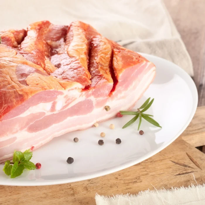 Füstölt szalonna félbevágva tányéron, mellette fűszerek