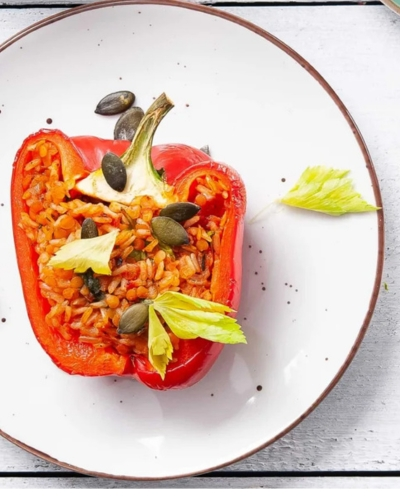 Rizzsel, lencsével és paradicsommal töltött paprika fehér tányéron