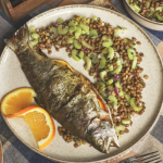 Egészben sült pisztráng zelleres lencsesalátával, félbevágott narancsszelettel tálalva tányéron