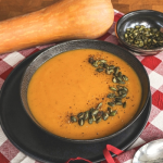 Sütőtök főzelék tányérban, dekorációként egész sütőtök mellette