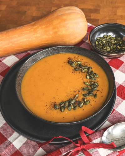 Sütőtök főzelék tányérban, dekorációként egész sütőtök mellette