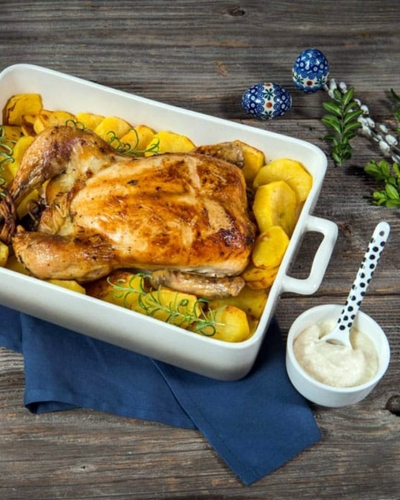 Tanyasi egész csirke tepsiben burgonyaágyon tálalva, mellette szósz