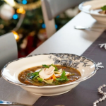 Gombaleves karácsonyi asztalon dekorációkkal, fehér tányérban