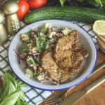 Zöldfűszeres tarja salátával tányérban, mellette uborka, paradicsom, saláta