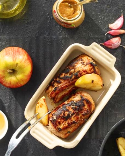 Egészben sült karaj almával tepsiben asztalon, mellette alma
