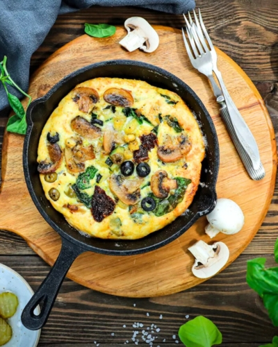 Frittata szárított paradicsommal serpenyőben fa deszkán tálalva