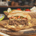 Házi sajtburger félbevágva fa deszkán, uborkával, répával, húspogácsával, sajttal