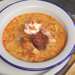 Korhelyleves tejföllel és kolbászkarikával tálalva tányéron