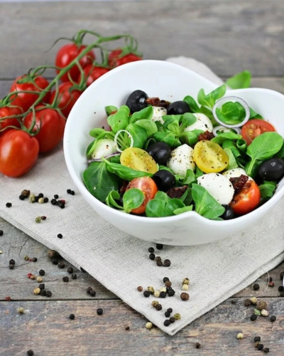 Mozzarellás paradicsomsaláta salátás tálban, paradicsomfürtökkel díszítve