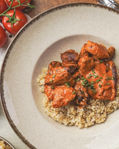 Fűszerpaprikás-paradicsomos csirke tejszínes szószban, bulgurral tálalva tányéron