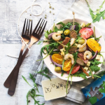 Rukkolasaláta pikáns szalámival evőeszközökkel asztalon tányéron