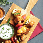 Csirkés saslik joghurtos szósszal tálalva fa deszkán