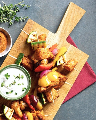 Csirkés saslik joghurtos szósszal tálalva fa deszkán