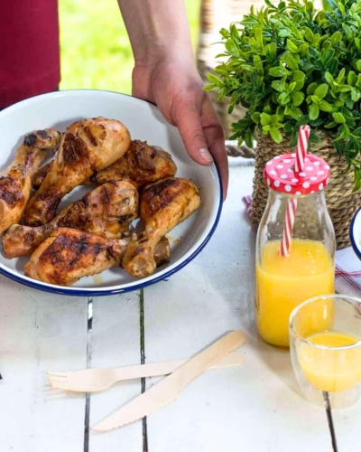 Sörben pácolt csirkecomb tálban, mellette narancslé