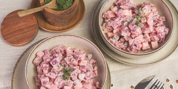 Majonézes céklasaláta kaporlevéllel megszórva egy salátás tálban, fa asztalon, kaporral tálalva